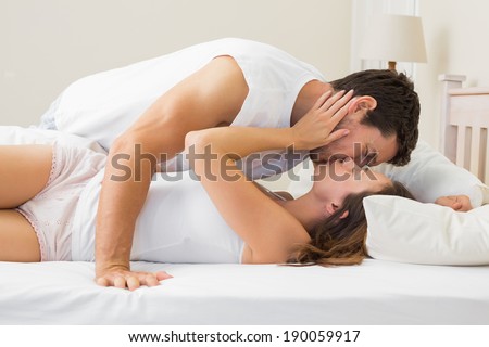 Side view of a relaxed young couple kissing in bed at home
