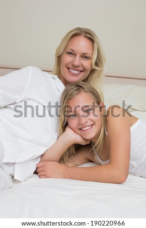 Portrait of happy woman with daughter lying in bed