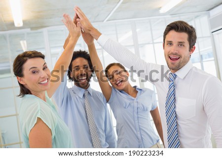 Portrait of business team joining hands together in bright office
