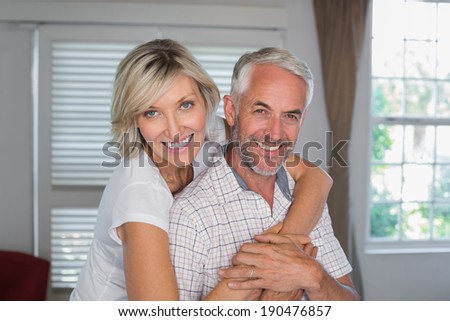 Portrait of a happy woman embracing mature man from behind at home