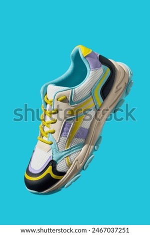 White sneaker with colored accents on blue background, Fashionable sport shoe with colorful backdrop. Studio shot of shoes for shop advertisement, creative minimalist style