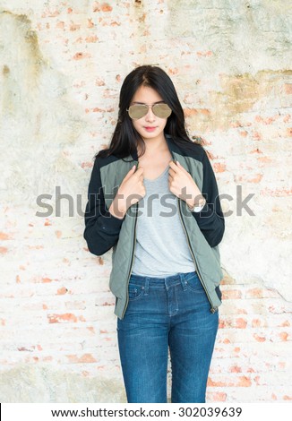 Beautiful young woman in Skinny jeans against an old brick wall