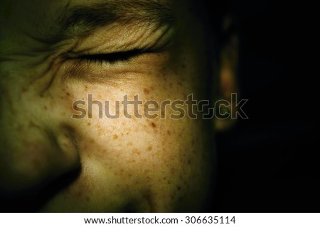Frowning Girl\'s face in pain on a dark background.