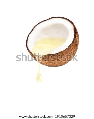 Coconut oil dripping from coconut fruits cut in half isolated on white background.