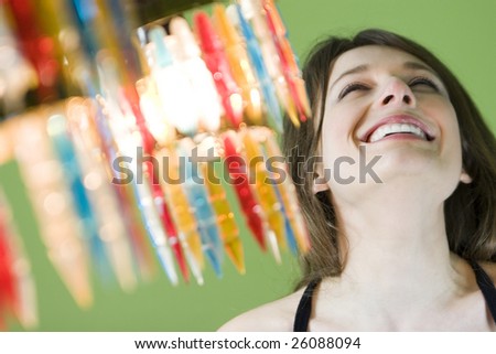 Portrait of beautiful smiling woman on green background with colourful chandelier.