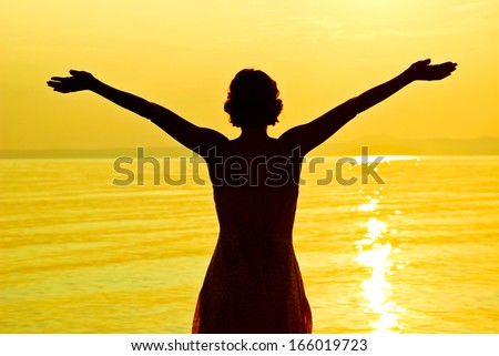 Meeting a sun. Silhouette of young beautiful woman at seashore
