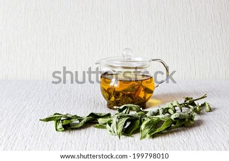 Green tea in glass teapot with fresh dry mint leaves on textured linen background