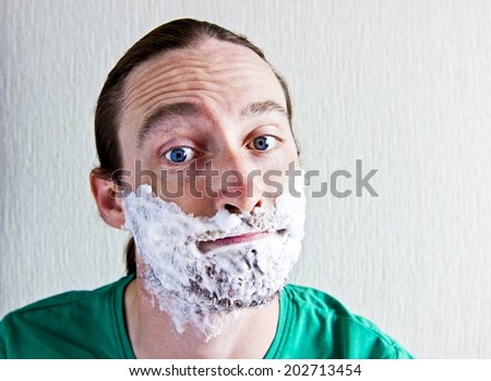 Portrait of handsome bearded young man with shaving foam on funny face