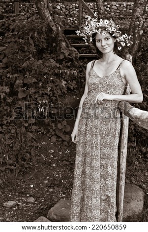 Portrait of the young beautiful smiling woman on the old bridge outdoors with field flowers. Image in black and white colors