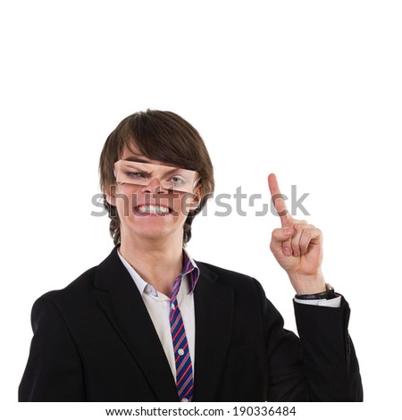 Funny young man with fake eyes making a face and pointing up. Head and shoulders studio shot isolated on white.