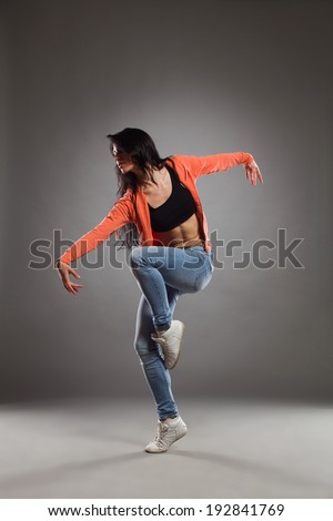 The dancer posing. Female dancer posing on one leg and arms outstretched. Full length studio shot on gray background.