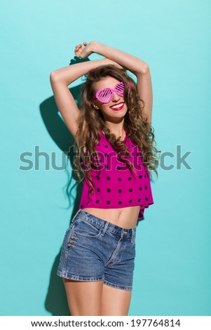 Enjoy the summer. Smiling beautiful young woman posing in sunlight. Three quarter length studio shot on teal background.