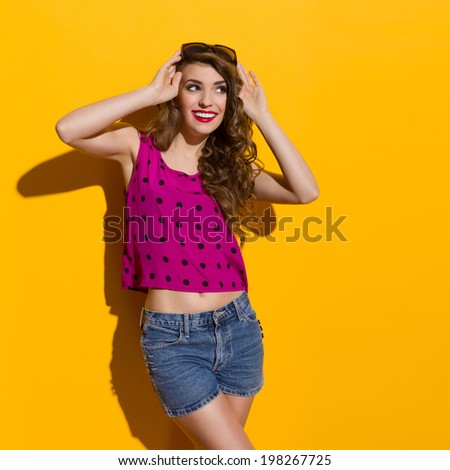 Sexy lady is looking at copy space. Three quarter length studio shot on yellow background.