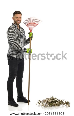 Smiling handsome man is standing with a leaf rake. Full length studio shot isolated on white. Stock fotó © 