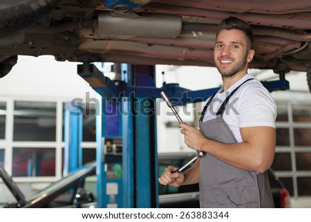 Man in workwear posing with a ratchet wrench