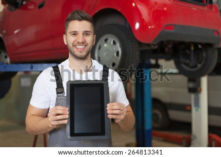 Car inspection approved. Smiling man in workshop presenting a digital tablet.