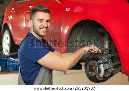 Fixing a car brakes. Smiling mechanic repairing a car brakes in auto mechanic shop