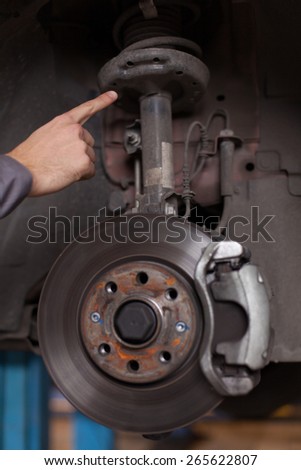 Hand pointing at a car suspension