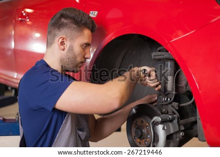 Repairing a car suspension. Smiling mechanic fixing a car suspension in auto mechanic shop