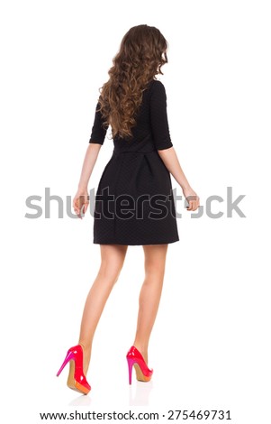 Walking Slim Woman in Black Mini Dress and Red High Heels, Rear View. Full length studio shot isolated on white.
