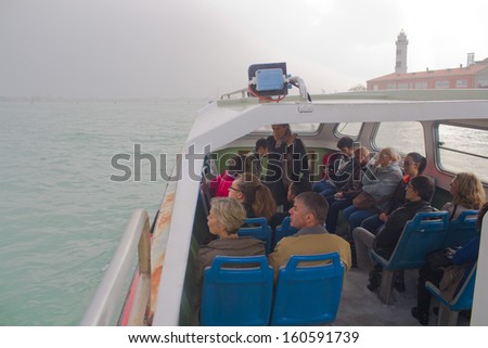 VENICE - OCTOBER 26, 2013 - A water bus or vaporetto full of tourists sets sail during a cloudy autumn in Venice.