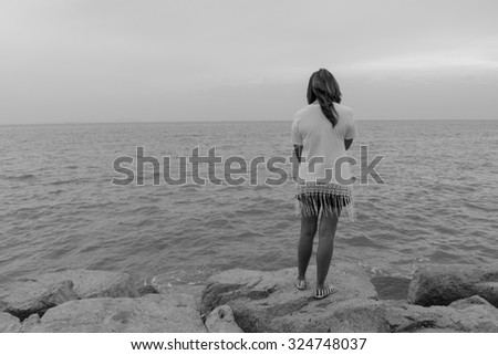 Alone woman stand on rock look sea view feel sad, Black and white tone