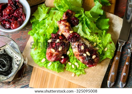 Chicken legs with cherry sauce, salad and pine nut. Top view