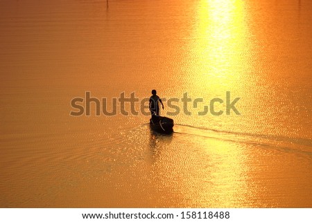 a man standing on a boat in the middle of the golden river