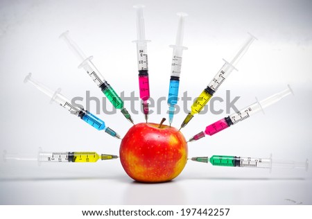Injection into red apple - Genetically modified fruit and syringe with colorful chemical GMO food