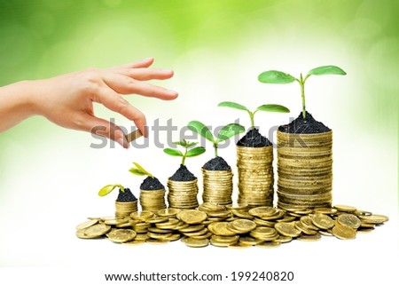 hand giving a golden coin to a tree growing on piles of golden coins - saving money