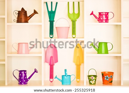 Shelf decoration with colorful gardening tools - watering cans, garden fork, rake, shovel, pail, bucket