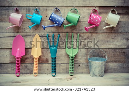 colorful gardening tools on wood background - fork, shovel, rake, bucket, watering can