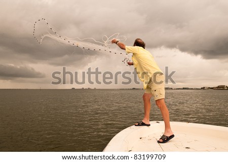 A man throwing a cast net off a bow of a boat