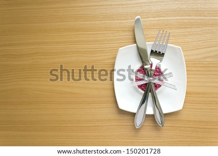 white square plate with fork and knife on a wooden table