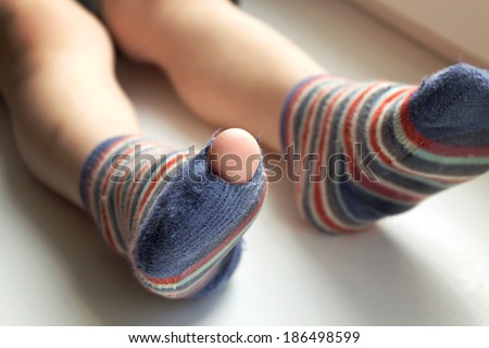 Worn out socks. Worn socks with a hole and a finger sticking out of them