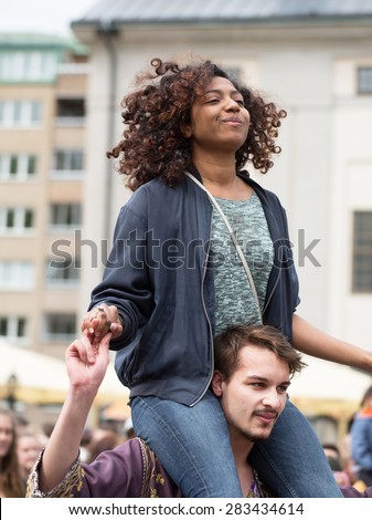 STOCKHOLM, SWEDEN - MAY 31, 2015. Peace and Love Parade. Street party in Stockholm, girl sitting on a man\'s shoulders. girl sitting on a man\'s shoulders