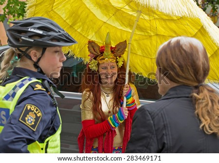 STOCKHOLM, SWEDEN - MAY 31, 2015. Peace and Love Parade. Street party in Stockholm. Policewoman in bicycle helmet, talking with festival participants.