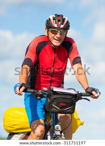 MORKO SWEDEN - AUG 29: Elderly happy man on the bike ride with the pack on the bike.