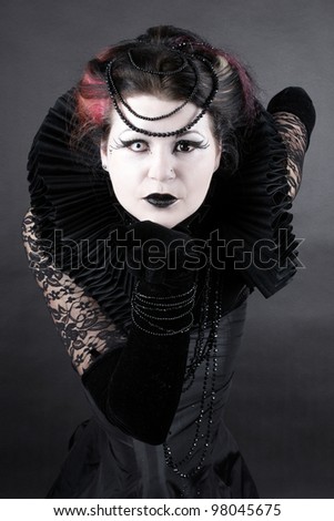 Woman dressed up in gothic style as dark queen in ancient victorian clothing