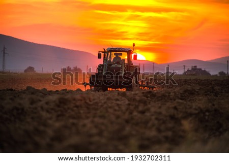 Farmer with tractor seeding crops at field on sunset 商業照片 © 