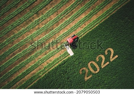 2022 Happy New year concept and red tractor mowing green field