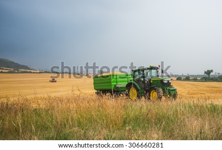 Varna, Bulgaria - June 20, 2015: Unidentified farmer driving a John Deere 6150 R agricultural tractor and trailer full of grain. John Deere 6150 R was manufactured in 2003-2008 in Germany.