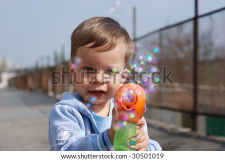 small boy playing with soap bubbles gun