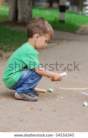 small boy drawing on the sidewalk with chalk