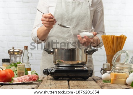 Chef in white uniform salts boiling water. Backstage of cooking pasta alla carbonara. Traditional italian dish on white background. Cooking process concept. Cookbook illustration.