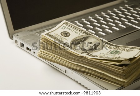 one hundred dollar bills on computer laptop