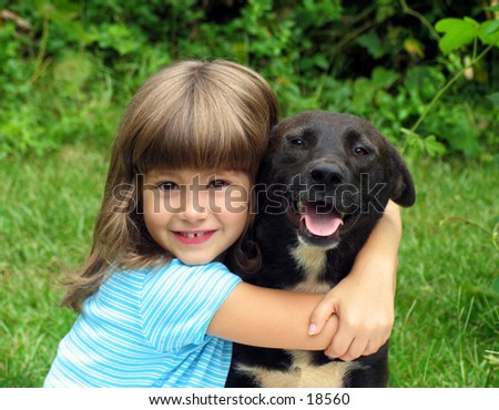 smiling little girl hugging a big black dog in an outdoor setting