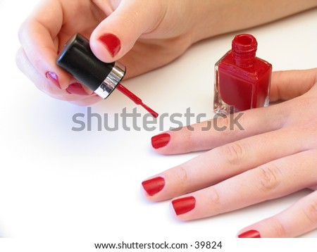 woman applying red nail polish on white background
