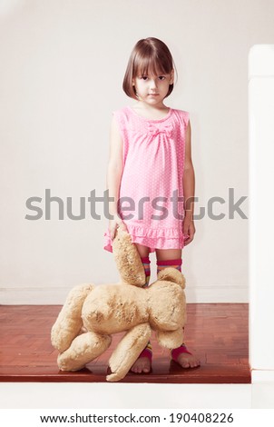 little girl standing on the porch and holding teddy bear