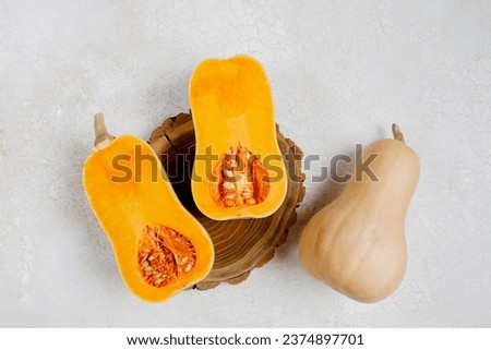 Similar – Image, Stock Photo Halved butternut squash on plate with cutlery and herbs at grey concrete kitchen table background.